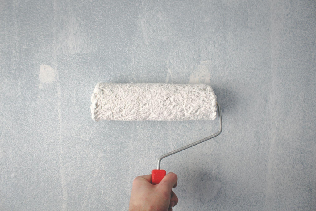 A person using a paint roller to paint a wall