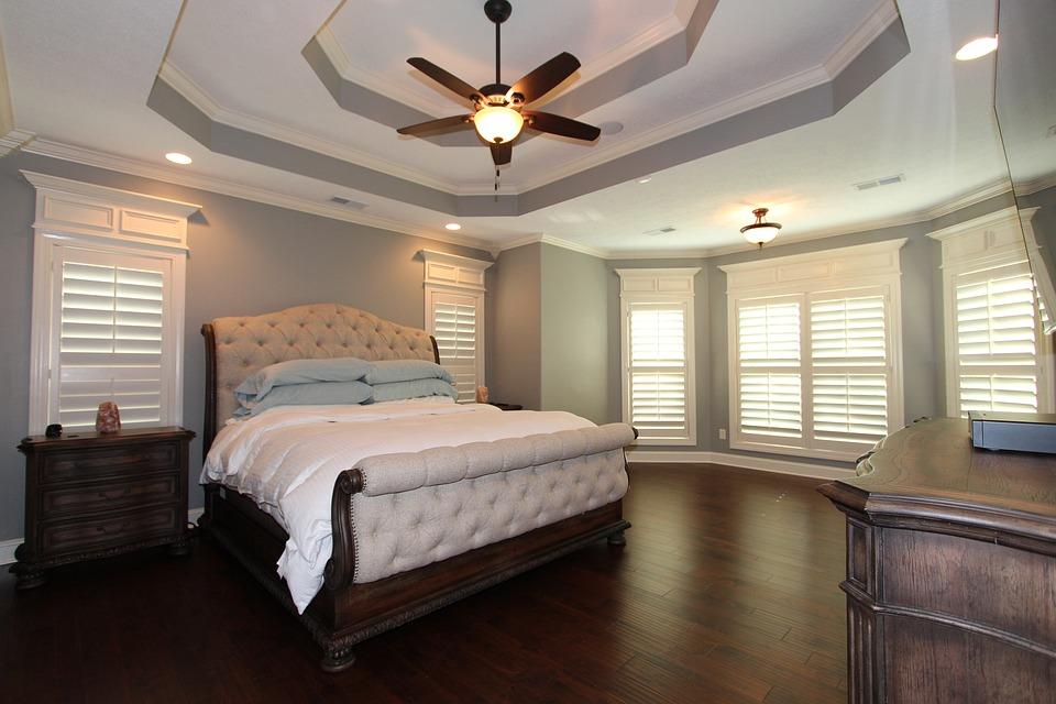 A simple master bedroom with a large bed and hardwood flooring